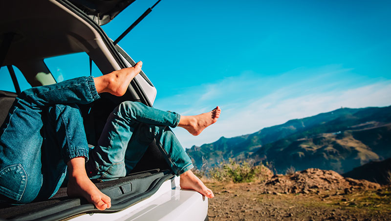 Image of a car somewhere in the mountains and two people sitting inside